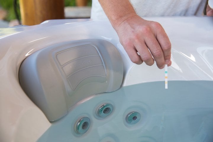 testing hot tub water with a pH test strip - clear up cloudy hot tub water 